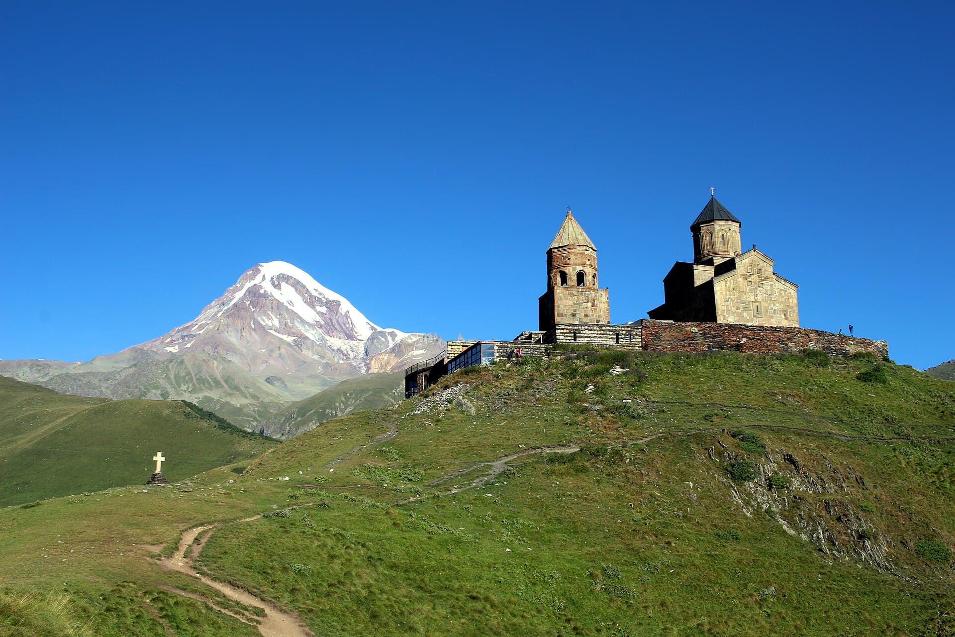 Gergeti Trinity Church on a grassy ridge with the snow-capped peak of Mount Kazbek behind it