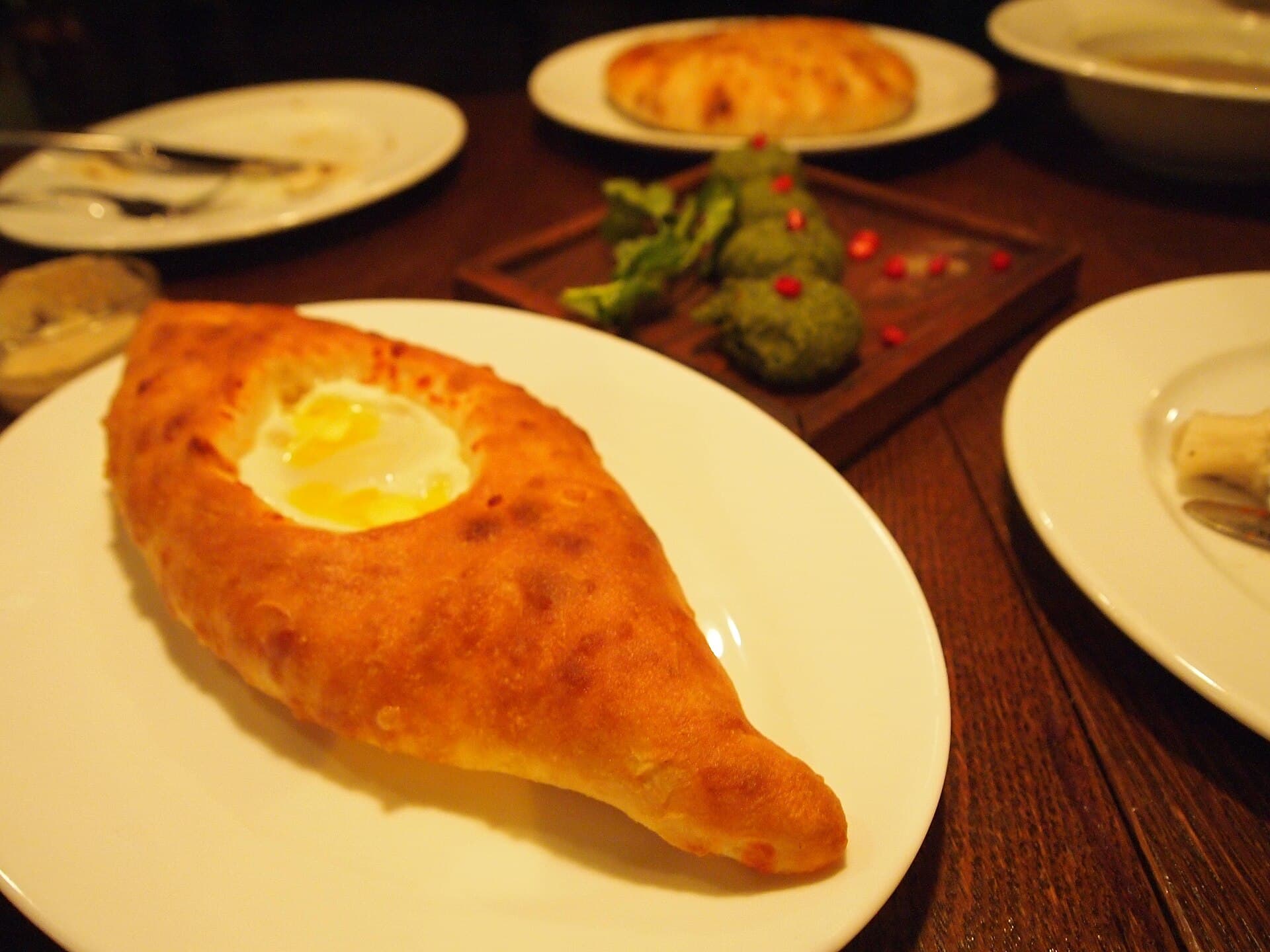 A boat-shaped Adjarian khachapuri with butter and egg, fresh from the oven on a supra table